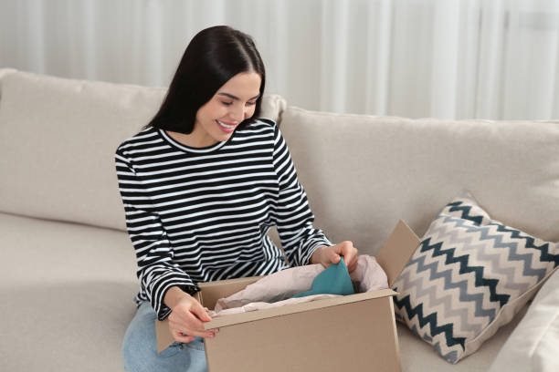 istock Happy woman unpacking parcel on sofa at home. Internet shopping 1808445532