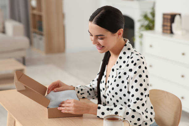 istock Happy young woman opening parcel at table indoors. Internet shopping 1808445538