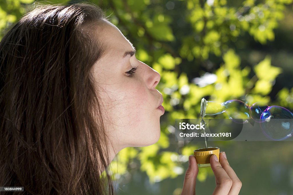 Giovane donna soffiare le bolle d'aria aperta - Foto stock royalty-free di Adolescente