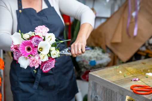 Female person making bouquet of colorful fresh flowers in flower shop