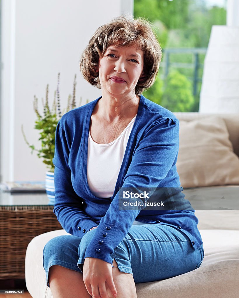 Attractive mature woman, Portrait Portrait of an attractive mature woman sitting on sofa at home and smiling,  55-59 Years Stock Photo