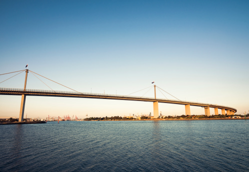 Australian flags on the towers of the West Gate Bridge, over the Yarra River.  The buildings of Melbourne's CBD are visible to the centre-right of the image.