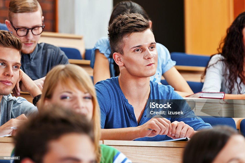 College students at the university College students sitting in the lecture hall at the university and listening to the lecture. Focus on young man. 20-24 Years Stock Photo