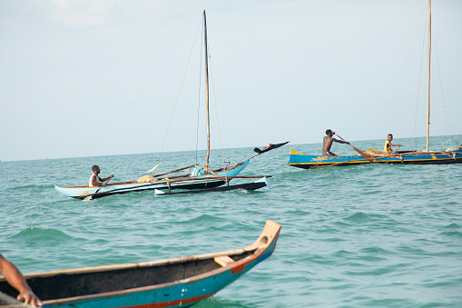 Morondava,Madagascar . 18 october 2023. Malagasy fisherman on homemade wooden old pirogue boat in ocean catches fish with net. selective focus, close-up