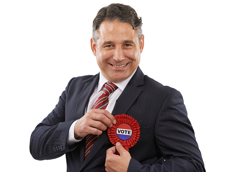 Portrait of a man in a suit with a voting ribbon on a white background