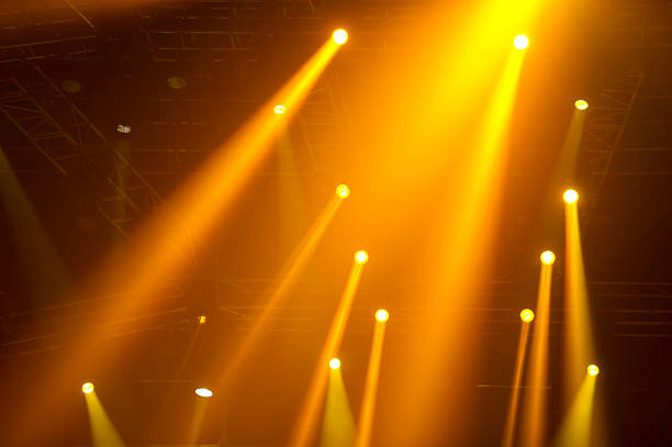 Bright Spotlights Golden spotlights in a concert. staging light stock pictures, royalty-free photos & images