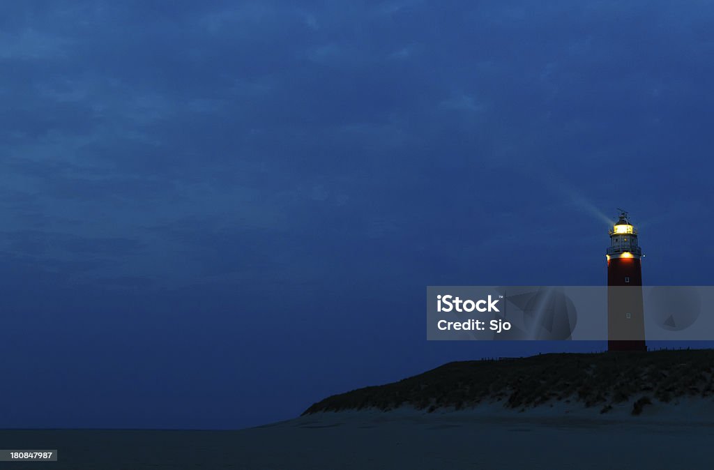 Lighthouse on a dune Lighthouse on top of a dune during a cloudy night. Lighthouse Stock Photo