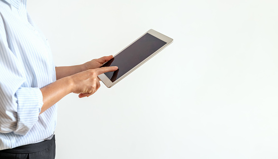 Isolated businesswoman using computer tablet, touching screen of digital tablet with finger.