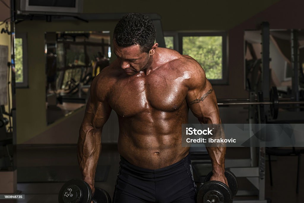 Homme dans la salle de sport spectacle de biceps curls avec haltère - Photo de Adulte libre de droits