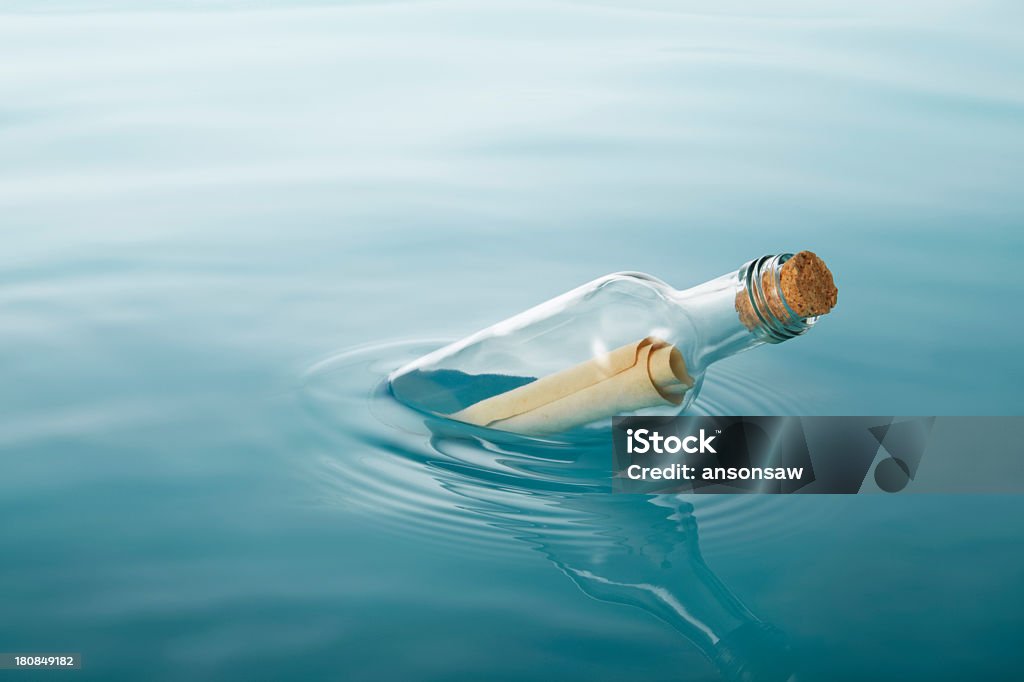 A message inside of a bottle floating in the water  message in a bottle floating on water Bottle Stock Photo
