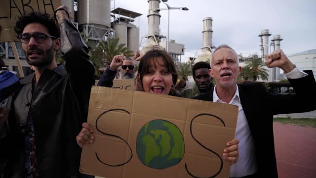Group of people at a refinery protesting against global warming.