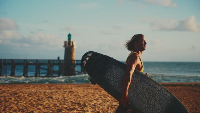 SLO MO Male surfer walking with surfboard on sunny ocean beach