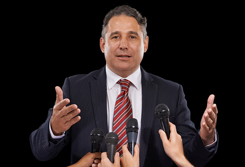Portrait of a mature man giving a press conference on a black background