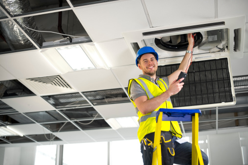 electrician fitting air conditioning to office interior