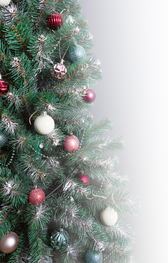 Christmas tree with branches sprinkled with hoarfrost and elegantly decorated with Christmas balls, beads, garlands.Vertical, closeup, copyspace
