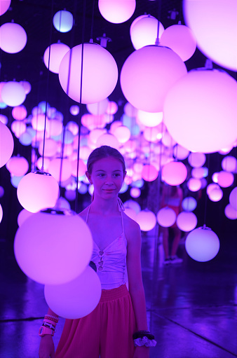 Portrait of young girl with pink lights balloons around her.