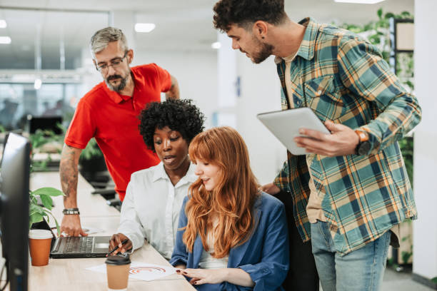 istock Multiracial colleagues using laptop and discussing work in an office 1808539153