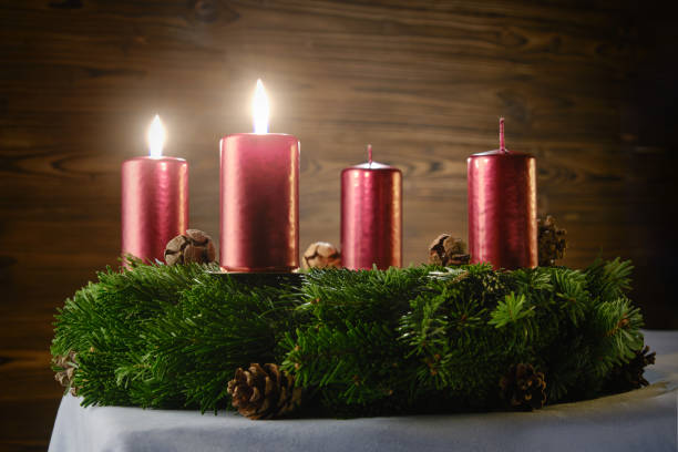 For the second Advent, two burning candles on an Advent wreath against a wooden background
