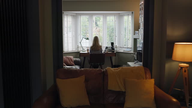 Woman, home office and remote work or dog love as freelance worker, back view at desk for project. Female person, typing and research as copy writing entrepreneur at apartment window, web as editor