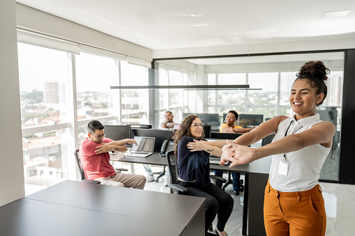 Workers doing stretching exercises before work in a telemarketing office