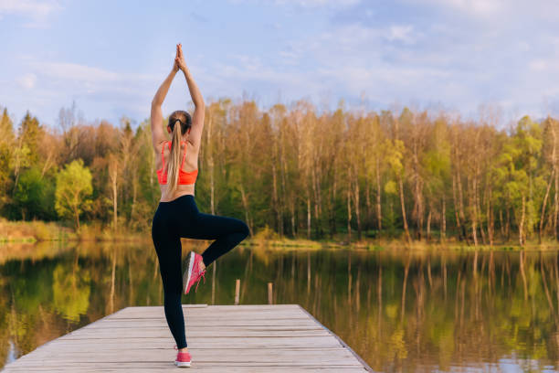istock back view woman in Vrikshasana pose, yoga practicing outdoors. W 1808608922
