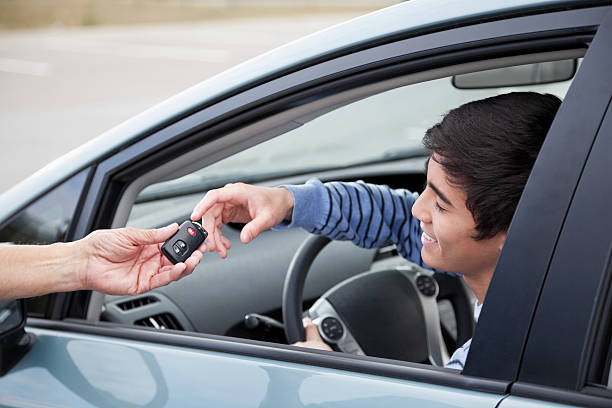 Teen driver getting car keys Teenage boy (17 years) sitting in driver's seat, getting keys to new car. teenager boy driving stock pictures, royalty-free photos & images