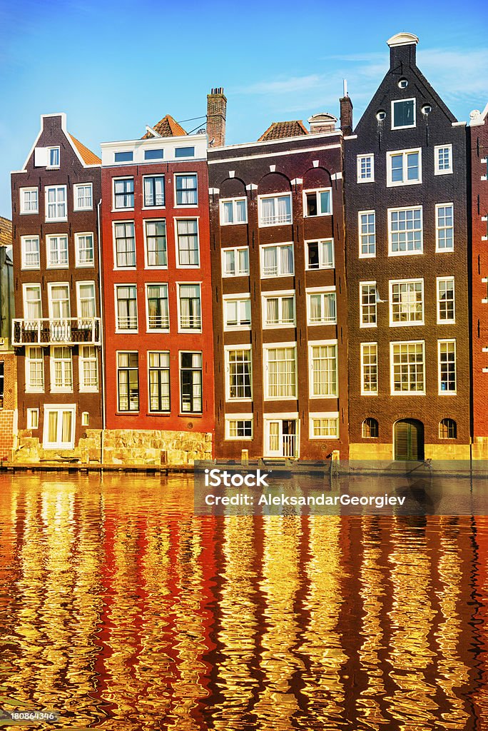 Typical Dutch Houses in the Center of Amsterdam Amsterdam City Scene. Visible are many typical dutch houses in raw and their reflection in the canal. Old 17th and 18th century brick houses along a canal in center of Amsterdam, Netherlands. Amstel River Stock Photo