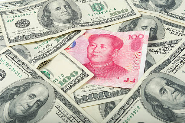 Currency Exchange One hundred China yuan paper currency in a pile of US dollar bills. mao original stock pictures, royalty-free photos & images