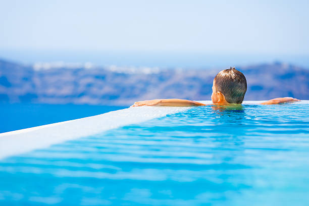 istock Kid in  infinity swimming pool on Santorini, Greece 180864672