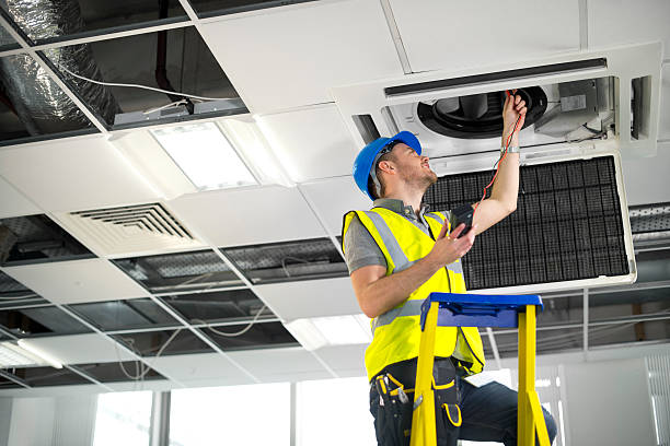 istock electrician fitting air conditioning to office interior 180864836