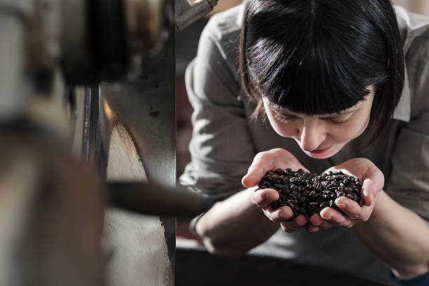 Female small business owner smelling fresh roasted coffee stock photo