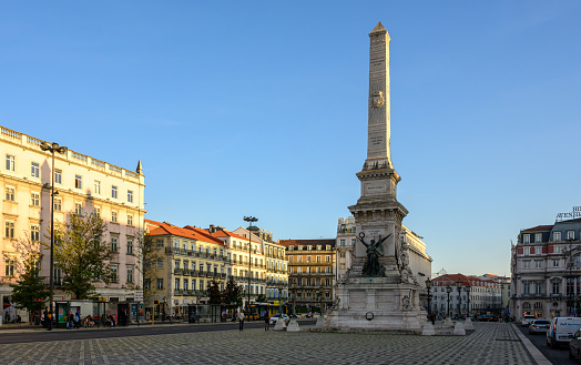 Lisbon, Portugal - Nov 14, 2023: Evening warm sunlight shines on the Monument and the Restauradores Square.