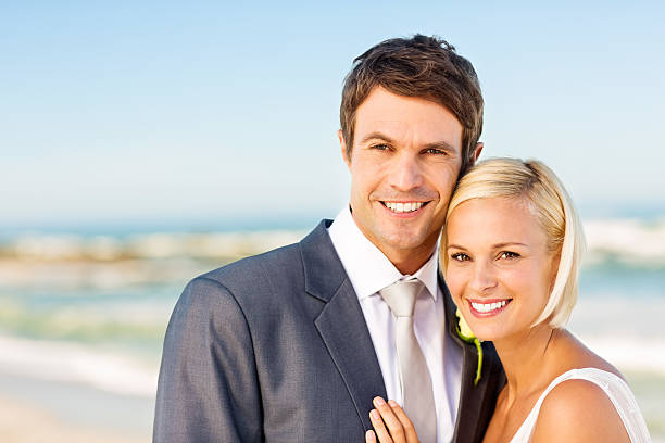 istock Newlywed Couple Smiling Together On Beach 180866825