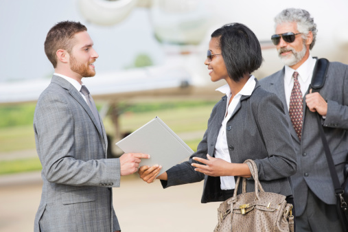 Business executives meeting colleage at airport after private jet flight