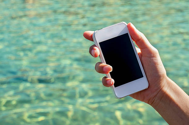 istock Woman using mobile phone by the beach 180867554