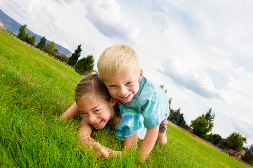 Two playful happy kids playing outdoors on a warm summer day at the park