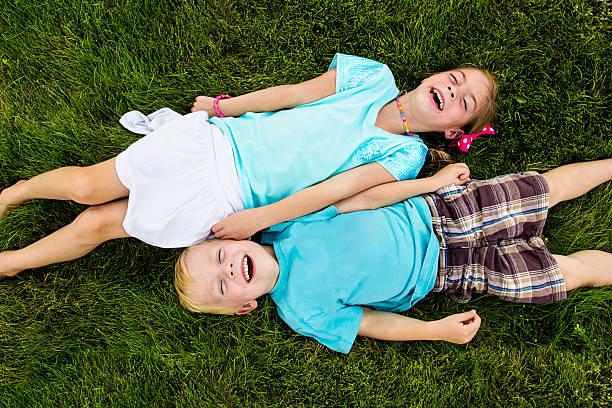 Two kids Laughing and having fun outdoors Two playful happy kids playing outdoors and having a big laugh together child laughing hysterically stock pictures, royalty-free photos & images