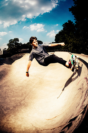 Young adult skater on sunny day in half pipe