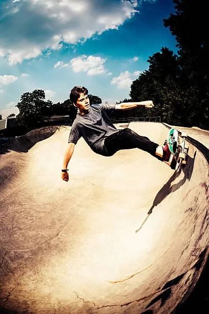 Young adult skater on sunny day in half pipe