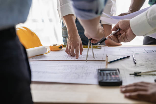 istock Concept architect, engineer, team holding pen, pointing architect, equipment on table with blueprints, ready to discuss home design in office. 1808685469