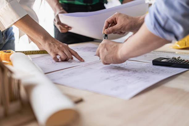 istock Concept architect, engineer, team holding pen, pointing architect, equipment on table with blueprints, ready to discuss home design in office. 1808685484