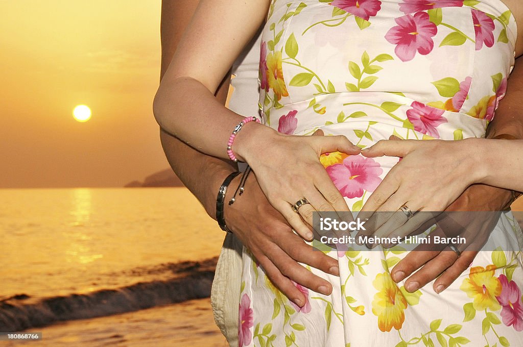 Femme enceinte et son mari au coucher du soleil - Photo de Abdomen libre de droits