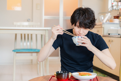 Young man eating dinner at a boarding house where he lives alone