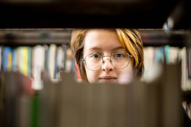 literarisches wunderland: der strahlende ausdruck eines teenagers inmitten einer welt voller bücher - canada manitoba university winnipeg stock-fotos und bilder