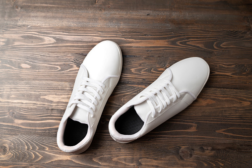 Closeup view of clean white sneakers on a wooden background