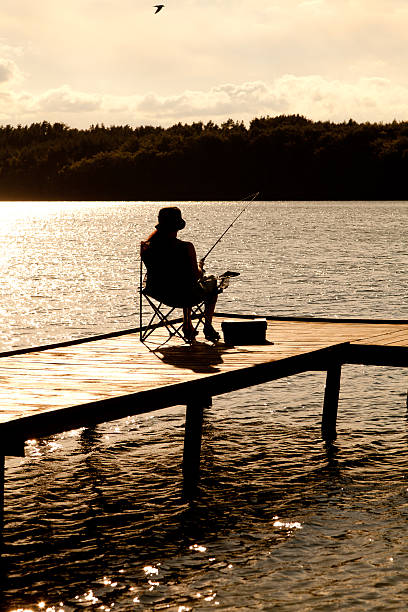 istock Angler fishes at sunset with bridge 180882549