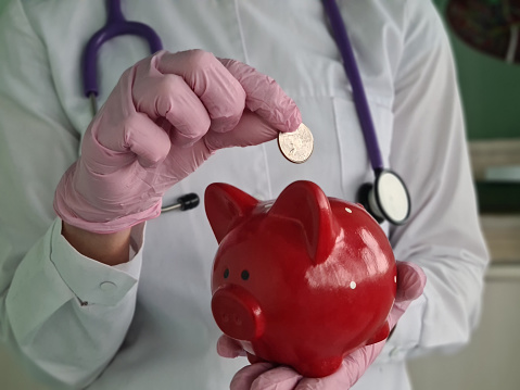 Woman put coin in piggy bank and put money aside for future. Health insurance