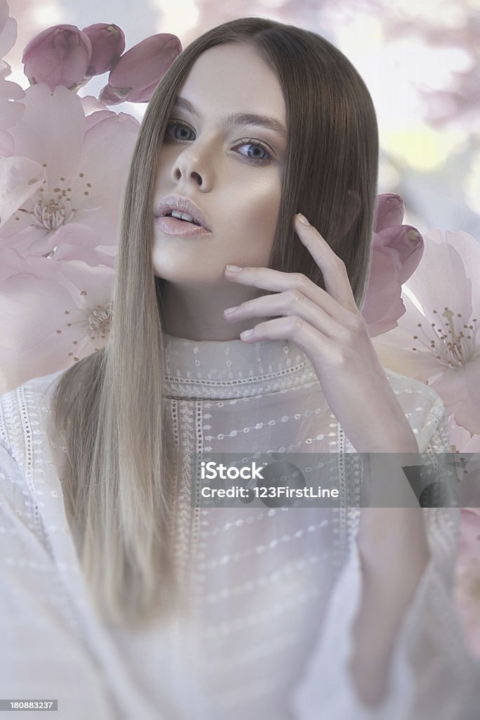 Hermosa mujer con la mano a su cara y flor de fondo - Foto de stock de A la moda libre de derechos