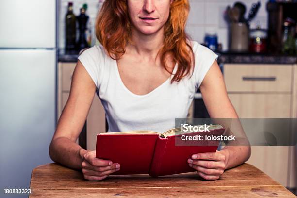 Женщина Читая Книгу В Ее Кухне — стоковые фотографии и другие картинки Бумага - Бумага, В помещении, Взрослый