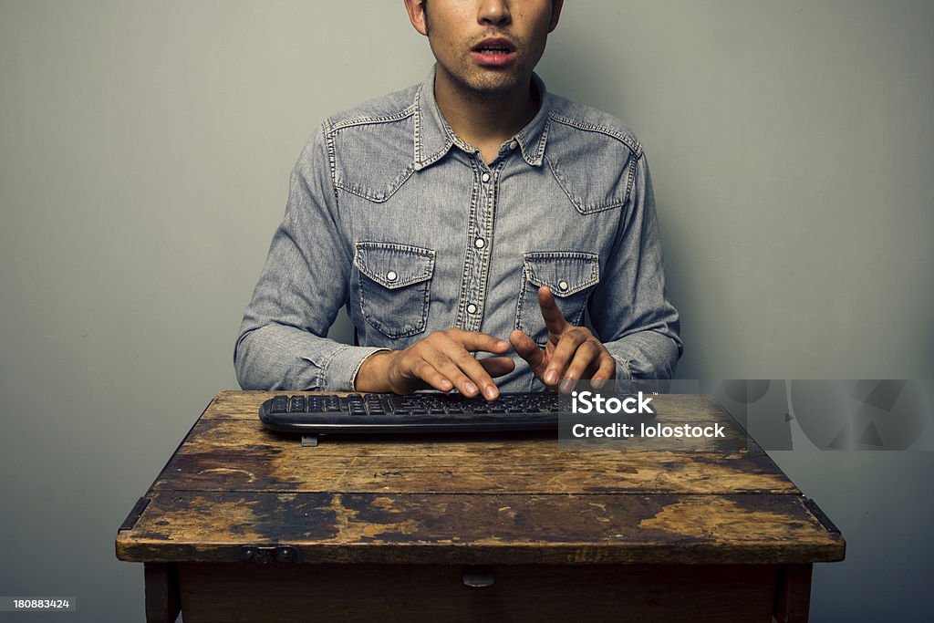 Man typing on keyboard at old desk Adults Only Stock Photo